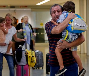 Juan Rojas, right, of Queens, hugs his 4-year-old grandson Elias Rojas, as his daughter-in-law Cori Rojas, left, carries her daughter Lilly, 3, through the terminal at JFK airport after Cori arrived on a flight from San Juan, Puerto Rico. (AP Photo/Julie Jacobson)