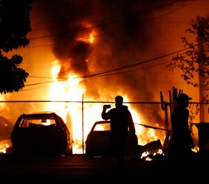 People watch a fire Friday, May 29, 2020, in Minneapolis. Protests continued following the death of George Floyd who died after being restrained by Minneapolis police officers on Memorial Day. (AP Photo/Julio Cortez)