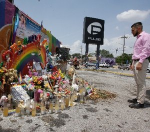 In this Tuesday, May 30, 2017 photo, Marco Quiroga, who works to support LGBTQ and social-justice causes in central Florida, reflects in front of one of the memorials at the Pulse Nightclub in Orlando, Fla.