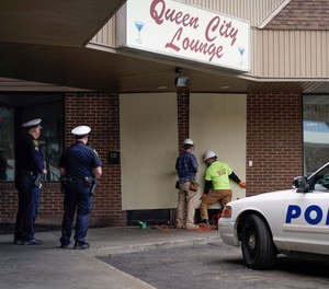 Police officers watch as workers board up the Queen City Lounge in Cincinnati, Ohio. (Photo/TNS)