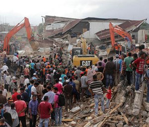Rescuers use excavators to search for victims under the rubble of collapsed buildings after an earthquake in Pidie Jaya, Aceh province, Indonesia. (AP Photo/Heri Juanda)