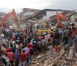 Rescuers use excavators to search for victims under the rubble of collapsed buildings after an earthquake in Pidie Jaya, Aceh province, Indonesia.