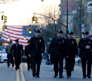 New York City police officers walk toward Christ Tabernacle Church before funeral services for officer Rafael Ramos at in the Glendale section of Queens.