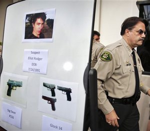 In this May 24, 2014, file photo, Santa Barbara County Sheriff Bill Brown, right, walks past a board showing the photos of gunman Elliot Rodger.