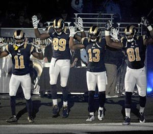 Members of the St. Louis Rams raise their arms in awareness of the events in Ferguson, Mo., as they walk onto the field during introductions before an NFL football game against the Oakland Raiders, Sunday, Nov. 30, 2014, in St. Louis.
