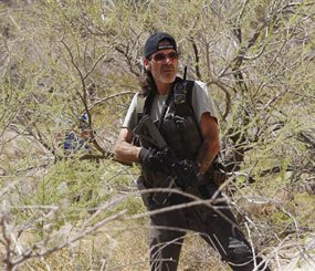An armed civilian waits nearby in some bushes as the Bundy family and their supporters gather together under the I-15 highway just outside of Bunkerville, Nev. in order to confront the Bureau of Land Management and demand the release of their impounded cattle on April 12, 2014.