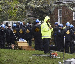 Rescue workers, police and fire department members wait to remove the bodies of a mother and child who were killed by a falling tree as Hurricane Florence made landfall in Wilmington, N.C. (Photo/AP)