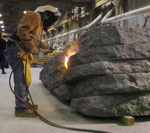 In this Tuesday, Jan. 8, 2019 photo, a worker uses a torch to finish a granite monolith at Rock of Ages in Barre, Vt. The monolith will be one of six that will be part of a permanent dedication to ground zero rescue and recovery workers expected to be unveiled in late May at the National September 11 Memorial & Museum in New York. (AP Photo/Lisa Rathke)