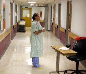 Richard Rivera, still in his Saint Anthony Hospital gown, pleads with a member of the medical detox team to get him into a sober-living facility near his family in Chicago. (AP Photo/Charles Rex Arbogast)