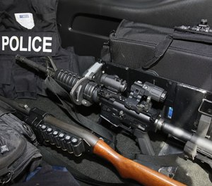 An AR-15 rifle, a shotgun, a vest and other safety gear is pictured in a police patrol car in Edmond, Okla., Thursday, July 14, 2016. (AP Photo/Sue Ogrocki)
