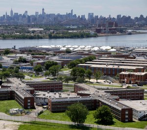 In a June 20, 2014, photo, the Rikers Island jail complex stands in New York with the Manhattan skyline in the background.