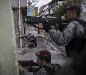 Brazil's national security force officers aim their weapons during a police operation in search for criminals in Vila do Joao, part of the Mare complex of slums, during the Summer Olympics in Rio de Janeiro, Brazil, Thursday, Aug. 11, 2016.