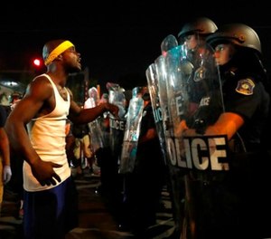 A man yells at police in riot gear just before a crowd turned violent Saturday, Sept. 16, 2017, in University City, Mo.