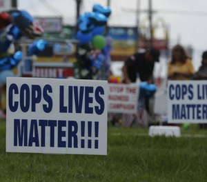 Some new signs have popped-up at the roadside memorial for the three Baton Rouge police officers who were killed on Sunday morning, along Airline Highway in Baton Rouge, La., on Tuesday, July 19, 2016.
