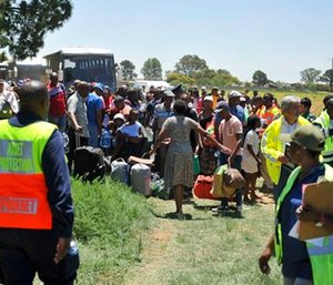 Train passengers are transferred to a bus at the scene of a train accident near Kroonstad, South Africa.