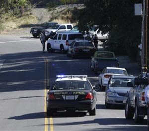 A California Highway Patrol car and other law enforcement vehicles set up a roadblock near Placer High School leading to a rural area where authorities are searching for an assailant, in Auburn, Calif., who shot three sheriff's deputies in two Northern California Counties, Friday, Oct. 24, 2014.