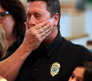 Chuck Hartung holds his daughter Haley, 8, during a prayer service at Wesley Memorial United Methodist Church for the victims of shootings. (AP Image)