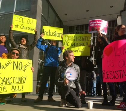 Protesters hold up signs outside a courthouse where a federal judge will hear arguments in the first lawsuit challenging President Donald Trump's executive order to withhold funding from communities that limit cooperation with immigration authorities Friday, April 14, 2017, in San Francisco.