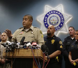San Bernardino County Sheriff's detective Jorge Lozano, center, answers questions from reporters during a news conference.