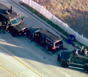 In this Dec. 2, 2015, file image, taken from video, armored vehicles surround an SUV following a shootout in San Bernardino, Calif.