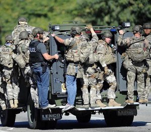 In this Dec. 2, 2015 file photo, an armored vehicle carries police officers near the scene of multiple shootings in San Bernardino, Calif.