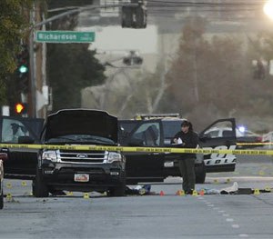 An investigator looks at a Black SUV that was involved in a police shootout with suspects, Thursday, Dec. 3, 2015, in San Bernardino, Calif. (AP Image)