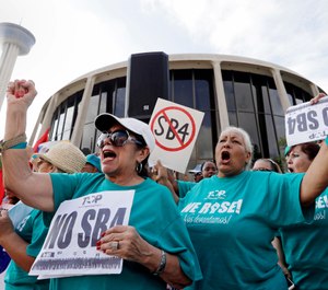 In this June 26, 2017, file photo, Lydia Balderas, left, and Merced Leyua, right, join others as they protest against a new sanctuary cities bill outside the federal courthouse in San Antonio. (AP Photo/Eric Gay, File)