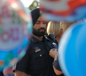 In this Aug. 29, 2015, photo, Harris County Sheriffs deputy Sandeep Dhaliwal gets a blue ribbon pinned to him during a vigil at the Chevron station in Houston, where Harris County deputy Darren Goforth was shot and killed previous night while he was refueling his vehicle. (Karen Warren/Houston Chronicle via AP)
