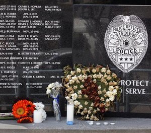 Flowers and candles were left at the San Diego Police Department memorial to officers who died in the line of duty the morning after an officer-involved shooting left one officer dead and one wounded.