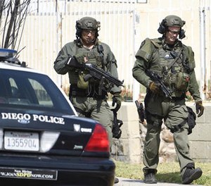 San Diego Police SWAT officers walk down the street after entering a house with a possible suspect inside Friday, July 29, 2016, in San Diego.