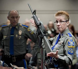 In this Jan. 28, 2013, file photo, firearms training unit Detective Barbara J. Mattson, of the Connecticut State Police, holds up a Bushmaster AR-15 rifle, the same make and model of gun used by Adam Lanza in the Sandy Hook School shooting, during a hearing of a legislative subcommittee, at the Legislative Office Building in Hartford, Conn.
