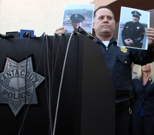 Santa Cruz Police Chief Kevin Vogel holds up photographs of slain detectives Loran