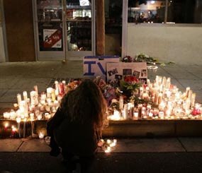 A woman places a candle in front of IV Deli Mart, where par of Friday night's mass shooting took place by a drive-by shooter, on Saturday, May 24, 2014, in the beach community of Isla Vista, Calif. (AP Image)