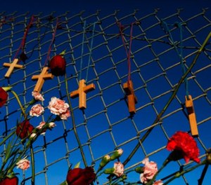 Crosses and flowers hang on a fence near Marjory Stoneman Douglas in Parkland, Fla., on Saturday, Feb. 16, 2018, in memory of the 17 people killed in a school shooting on Wednesday.