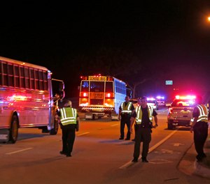 Police officers stand watch as spectators are bussed from a shooting incident at a practice football game between Dwyer and Palm Beach Central High School Friday, Aug. 17, 2018, in Wellington, Fla.