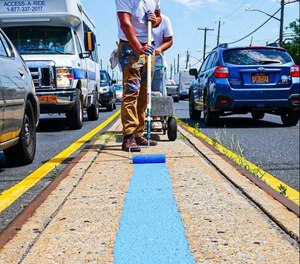Scott LoBaido paints a blue line along Hylan Boulevard in Staten Island, New York as a tribute to NYPD.