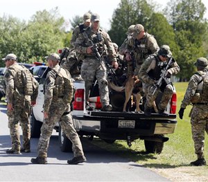 Law enforcement officers get off a truck as they return to their vehicles after searching a wooded area on Sunday, June 14, 2015.