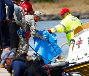 Water safety officials hand over possible debris from an Army UH-60 Black Hawk helicopter crash to military personnel stationed at a command center in a harbor.