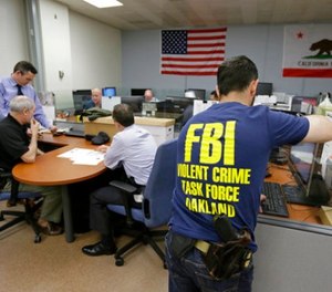 In this Friday, March 10, 2017, photo, Oakland police detectives and FBI agents work together in the offices of the Oakland Safe Streets Task Force in Oakland, Calif.