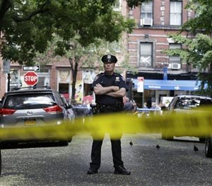 A police officer stands near a crime scene on Monday, July 28, 2014 in New York. Authorities say a sex-assault suspect got in a shootout with law enforcement in New York City that wounded the suspect, two federal marshals and a police officer. (AP Image)
