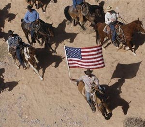 In this April 12, 2014, file photo, the Bundy family and their supporters fly the American flag as their cattle is released by the Bureau of Land Management back onto public land outside of Bunkerville, Nev.