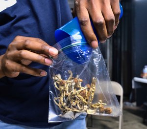 In this Friday, May 24, 2019 photo a vendor bags psilocybin mushrooms at a cannabis marketplace in Los Angeles. (AP Photo/Richard Vogel)