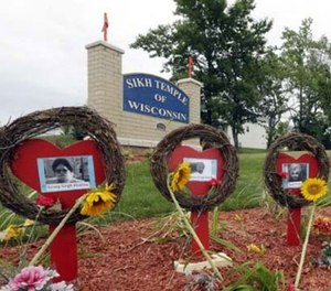 A makeshift memorial is seen before a candlelight vigil in the parking lot the Sikh Temple of Wisconsin Monday, Aug. 5, 2013, in Oak Creek, Wis. Monday is the one-year anniversary of the shooting rampage when a white supremacist at the temple where six people were killed. (AP Photo/Morry Gash)