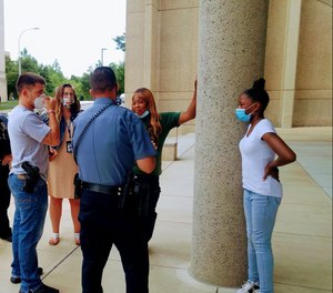 Shetara Sims and daughter Rakiya meet coworkers of the wounded officer after donating $100 they won with a lottery ticket.