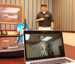 A holographic image of a human skeleton appears on a laptop computer while it's being controlled by David Blevins, in background, director of EMS programs at Roane State Community College.
