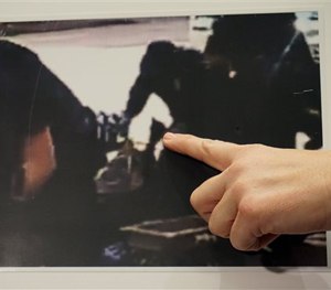 Los Angeles Police detective Meghan Aguilar points at a photo released by police that could indicate evidence of a suspect holding a police officer's gun.