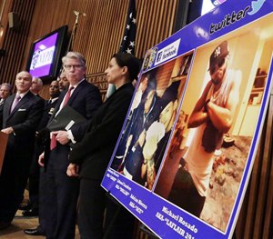 In this April 12, 2013 photo, NYPD officials stand next to photos that accused cocaine dealers posted on social media. The suspects posed with stacks of cash, guns and diamond-crusted watches.