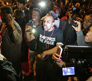 Crowds confront police near the scene in in south St. Louis where a man was fatally shot by an off-duty St. Louis police officer on Wednesday, Oct. 8, 2014.