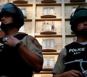 A guest of The Ritz-Carlton hotel watches as St. Louis County officers guard the front of the building from protesters Saturday, Sept. 23, 2017, in Clayton, Mo.