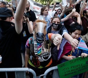 Counterprotesters, including one wearing a horse mask, line the route of the Straight Pride Parade in Boston, Saturday, Aug. 31, 2019.